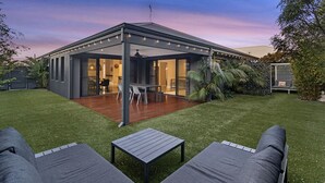Una casa moderna con un porche cubierto, un comedor y un jardín.