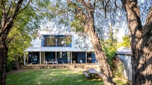 A two-story house with a covered porch, a barbecue area, and a picnic table in the yard. - Quindy Beach Cottage – Steps to the Bay (Quindalup)