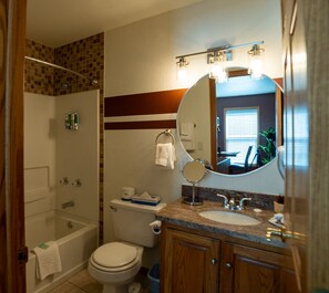 A bathroom with a bathtub, toilet, sink, and a large mirror.