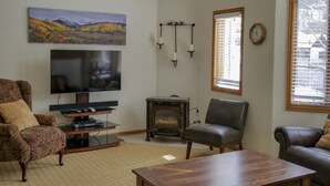 A living room with a television, a fireplace, and leather sofas. - Cascade Three Bedroom Three Bath C03 (Ouray)