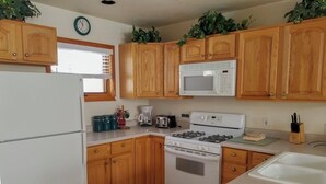 A kitchen with wooden cabinets, a white refrigerator, a microwave, a stove, and a sink. - Cascade Three Bedroom Three Bath C03 (Ouray)