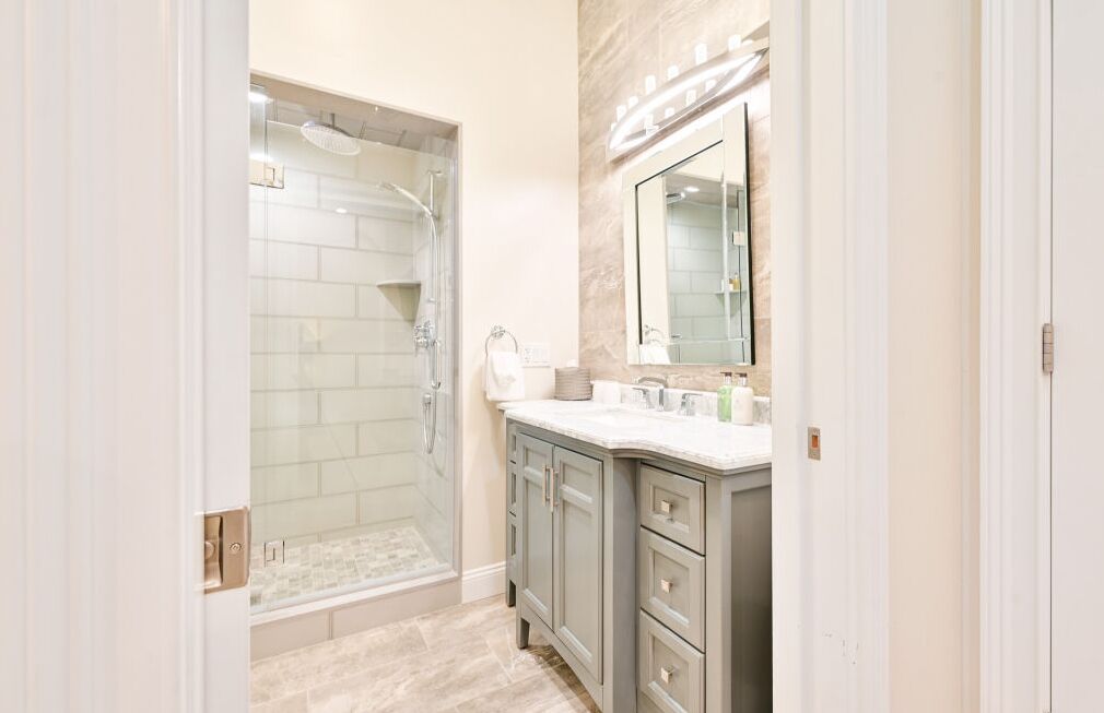 Une salle de bain avec une douche à parois de verre, un meuble-lavabo avec un miroir et un sol carrelé.