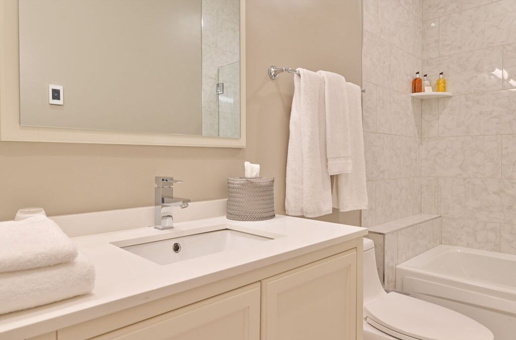 Un baño moderno con lavamanos, espejo y retrete.