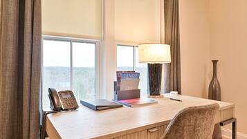 Une chambre d’hôtel équipée d’un bureau, d’un téléphone, d’une lampe et d’une fenêtre avec des rideaux.