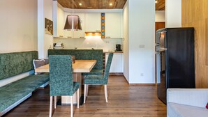 Una cocina moderna con techo de madera, asientos tapizados en verde y un refrigerador negro.