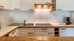 Una cocina moderna con armarios blancos, tiradores de madera, un lavabo doble y una cafetera.
