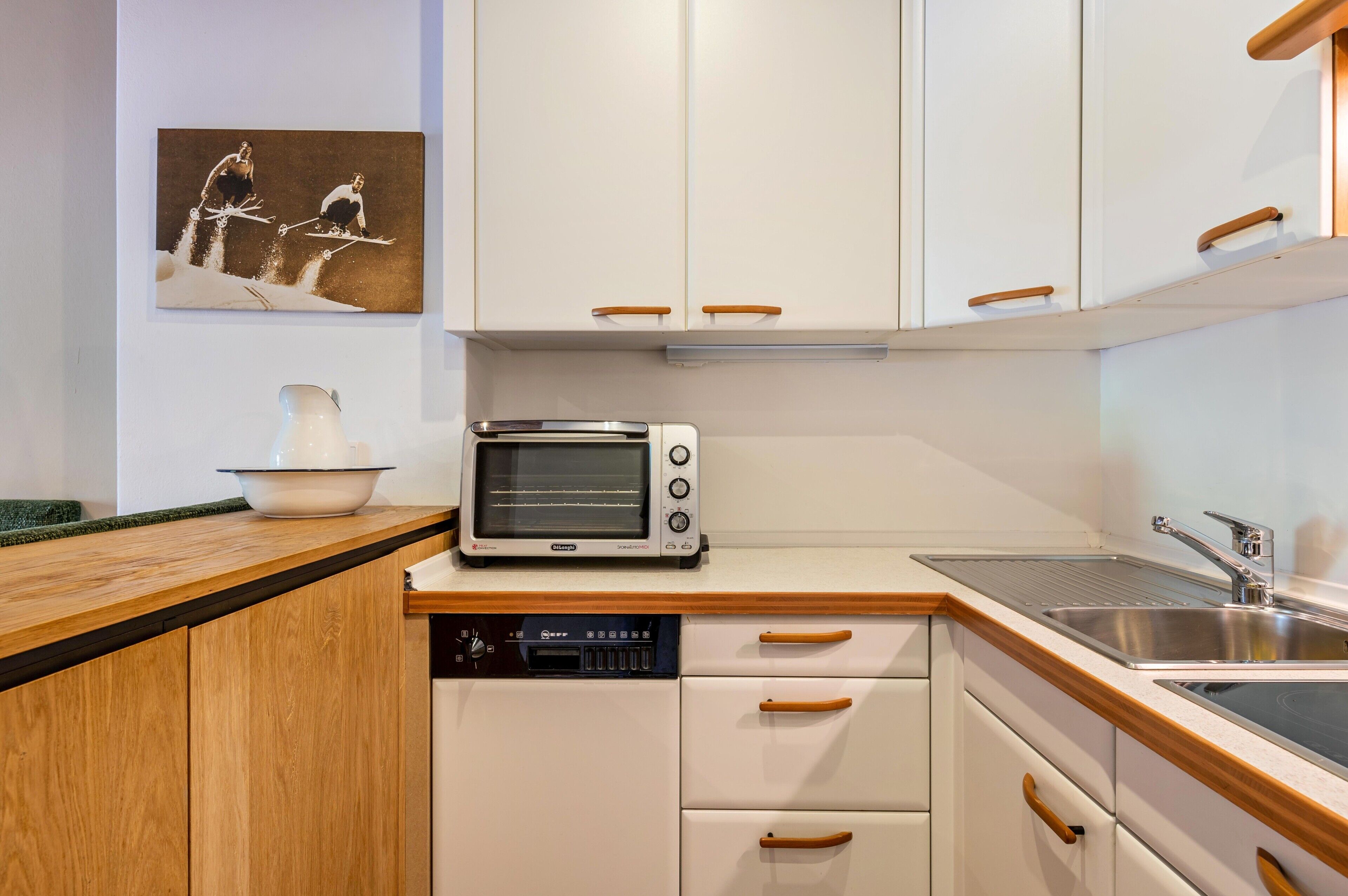 A kitchen with white cabinets, a toaster, a dishwasher, and a sink.
