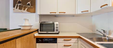 A kitchen with white cabinets, a toaster, a dishwasher, and a sink.