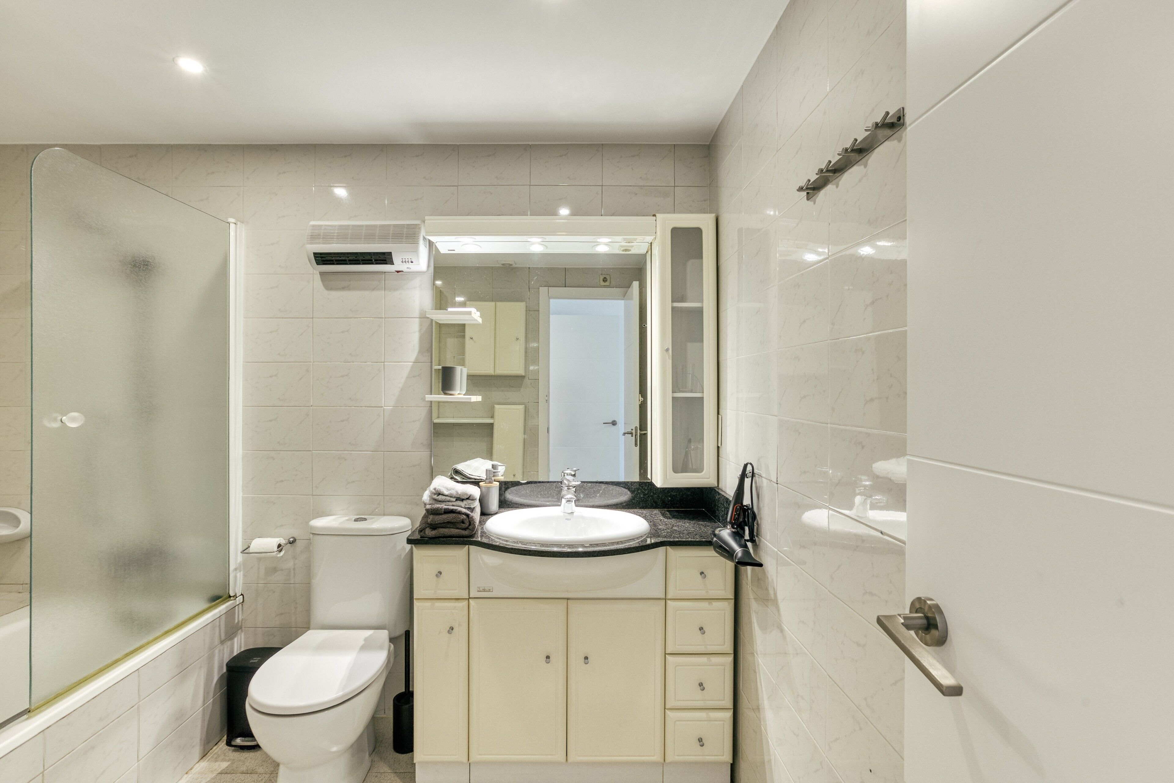 Une salle de bain moderne équipée de toilettes, d’un lavabo et d’une douche à parois de verre.