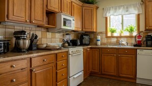 A kitchen with wooden cabinets, a microwave, a stove, and various appliances. - Alpenglow One Bedroom One Bath A18 (Ouray)
