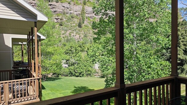 A wooden deck with a view of a green lawn and trees. - Cascade Three Bedroom Two Bath C07 (Ouray)