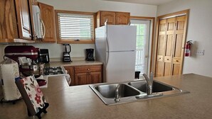 A kitchen with wooden cabinets, a stainless steel sink, a refrigerator, and a coffee maker. - Cascade Three Bedroom Two Bath C07 (Ouray)