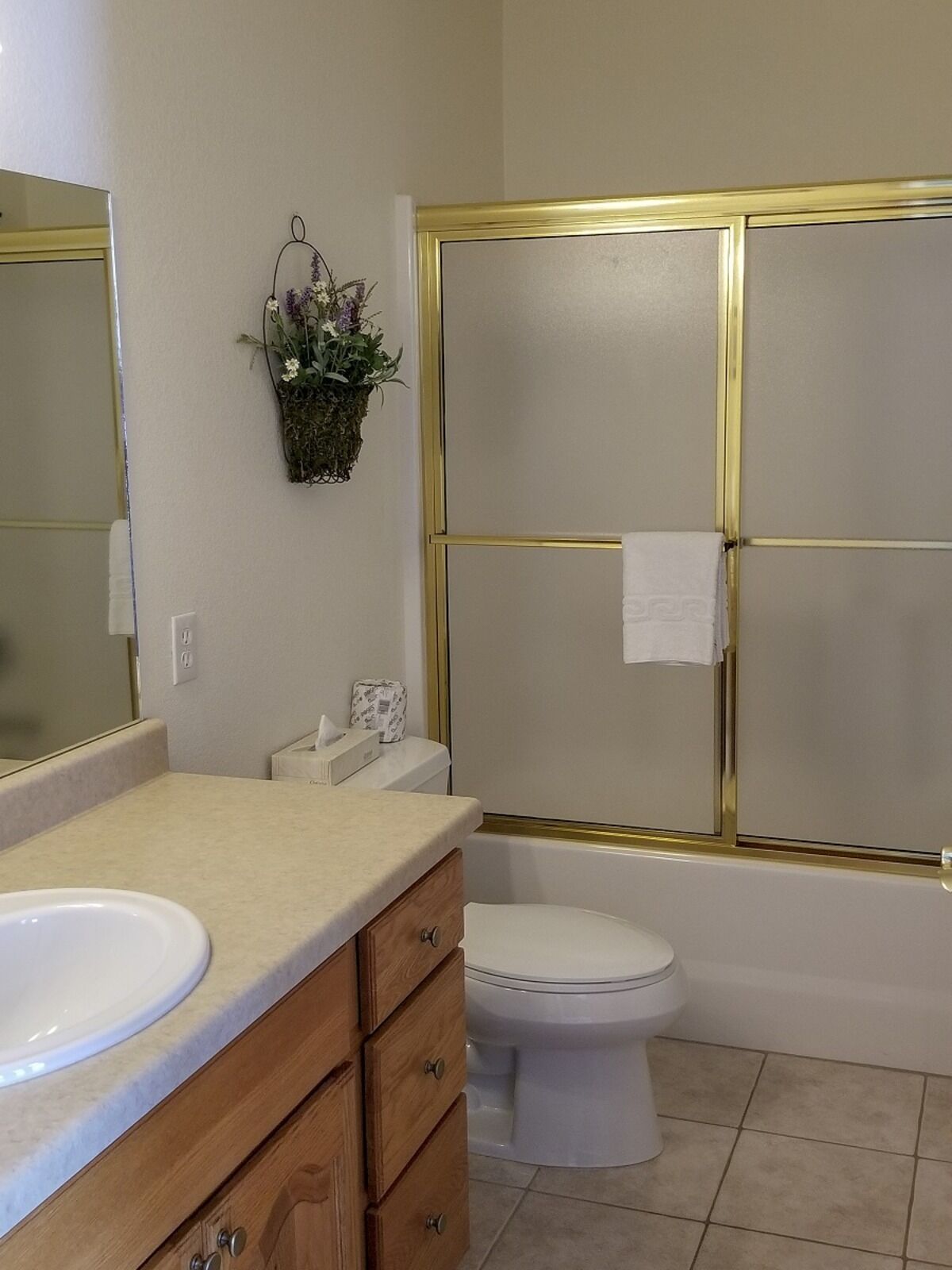 Une salle de bain avec un meuble-lavabo à deux vasques, des toilettes, une douche avec un cadre doré et un miroir.