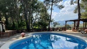 A swimming pool surrounded by trees, a wooden fence, and a pergola with flowers. - Country House 'El Pinar De La Loma' with Private Pool, Wi-Fi and Air Conditioning (Moratalla)