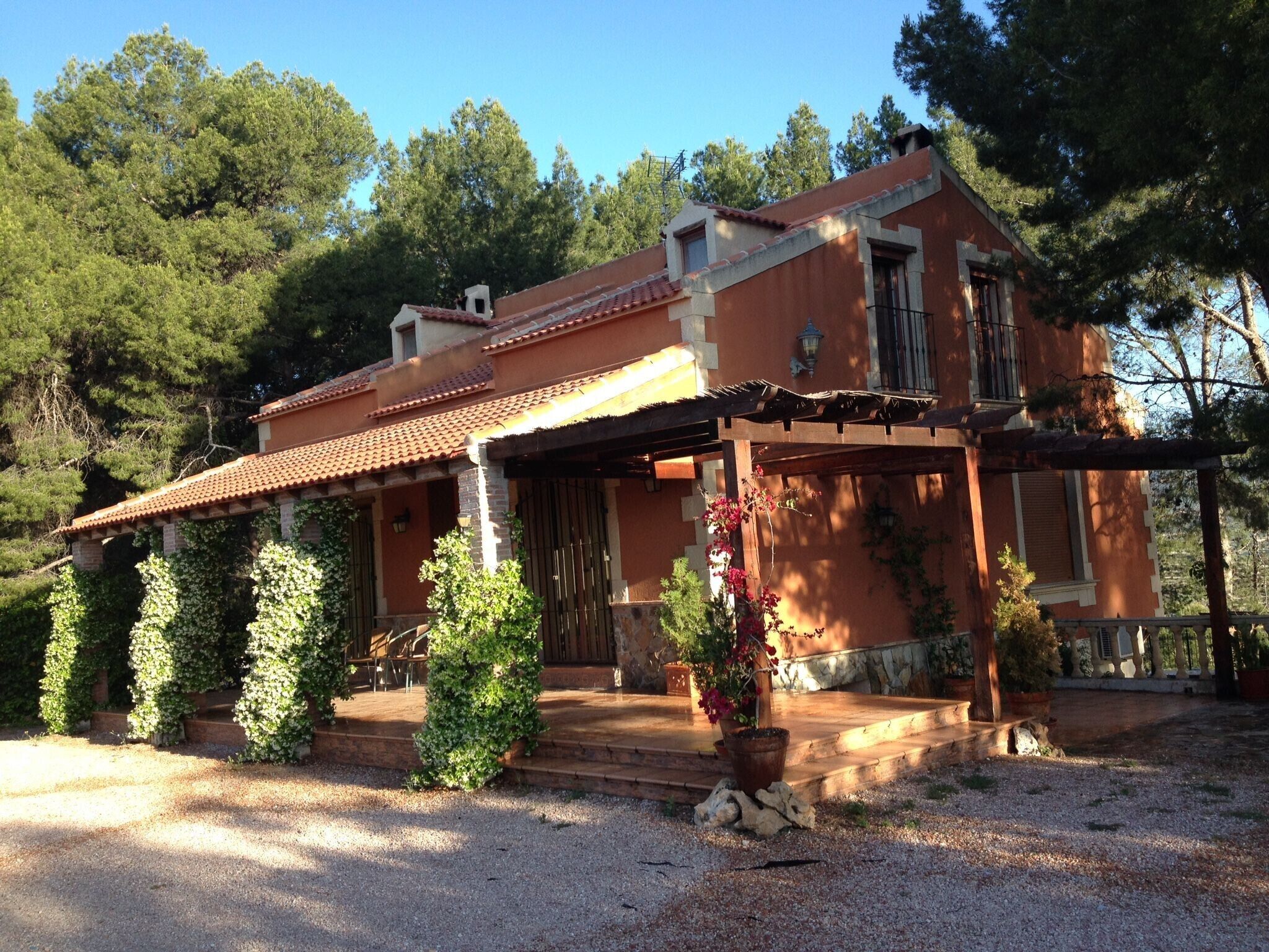 Una casa de dos pisos con techo de tejas, un porche cubierto y un camino de entrada de grava.