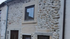 A stone building with two windows and a door.