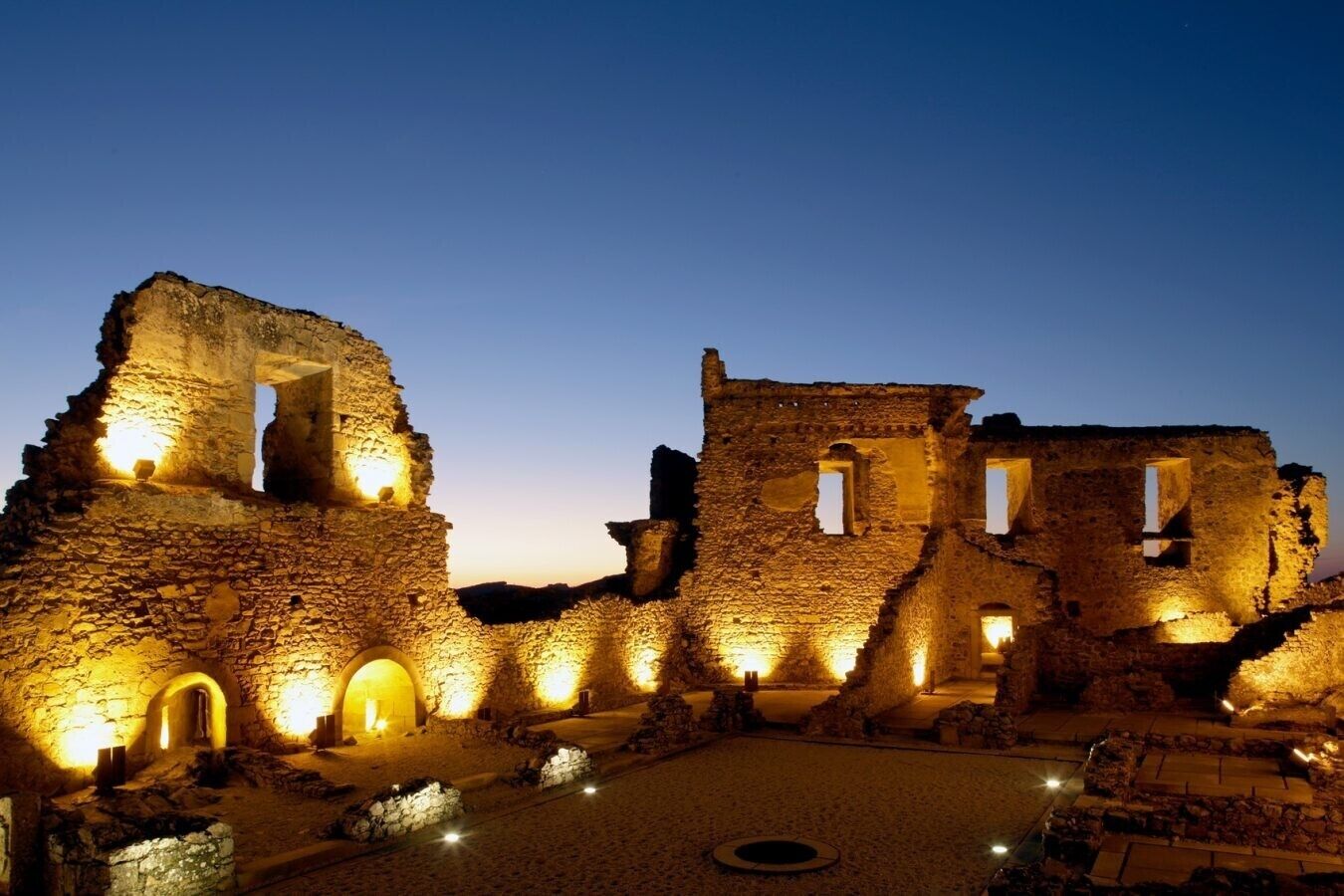 Ancient ruins with stone walls and arches, illuminated by warm lighting.