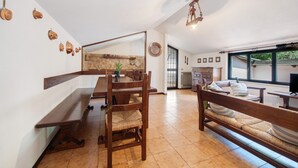 A spacious dining area with wooden furniture, a large mirror, and a view of the kitchen through an open door. - Apartment 'Appartamento Rupestre  2.0' with Private Terrace, Private Garden and Wi-Fi (Manerba del Garda)