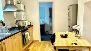 Et kompakt køkken med træskabe, en komfur og et spiseområde med bord og stole.