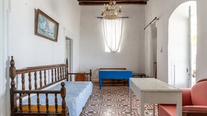 A room with a wooden bed, a blue bench, a white table, and a patterned floor. - Marino's Country House 1 Apartment with Sea View, Wi-Fi, and Air Conditioning (Sifnos)