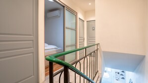 Una scala con ringhiera in metallo, una camera da letto con un letto e un condizionatore d'aria, e una porta con un piccolo adesivo.