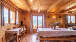 A wooden cabin with a dining area, a bed, and a view of mountains.