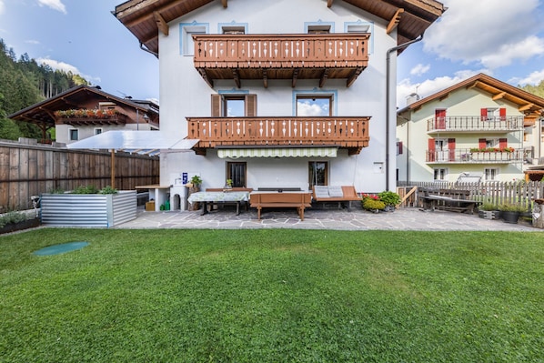 Un immeuble à plusieurs étages doté de balcons, d’un patio aménagé avec du mobilier d’extérieur et d’une pelouse bien entretenue.
