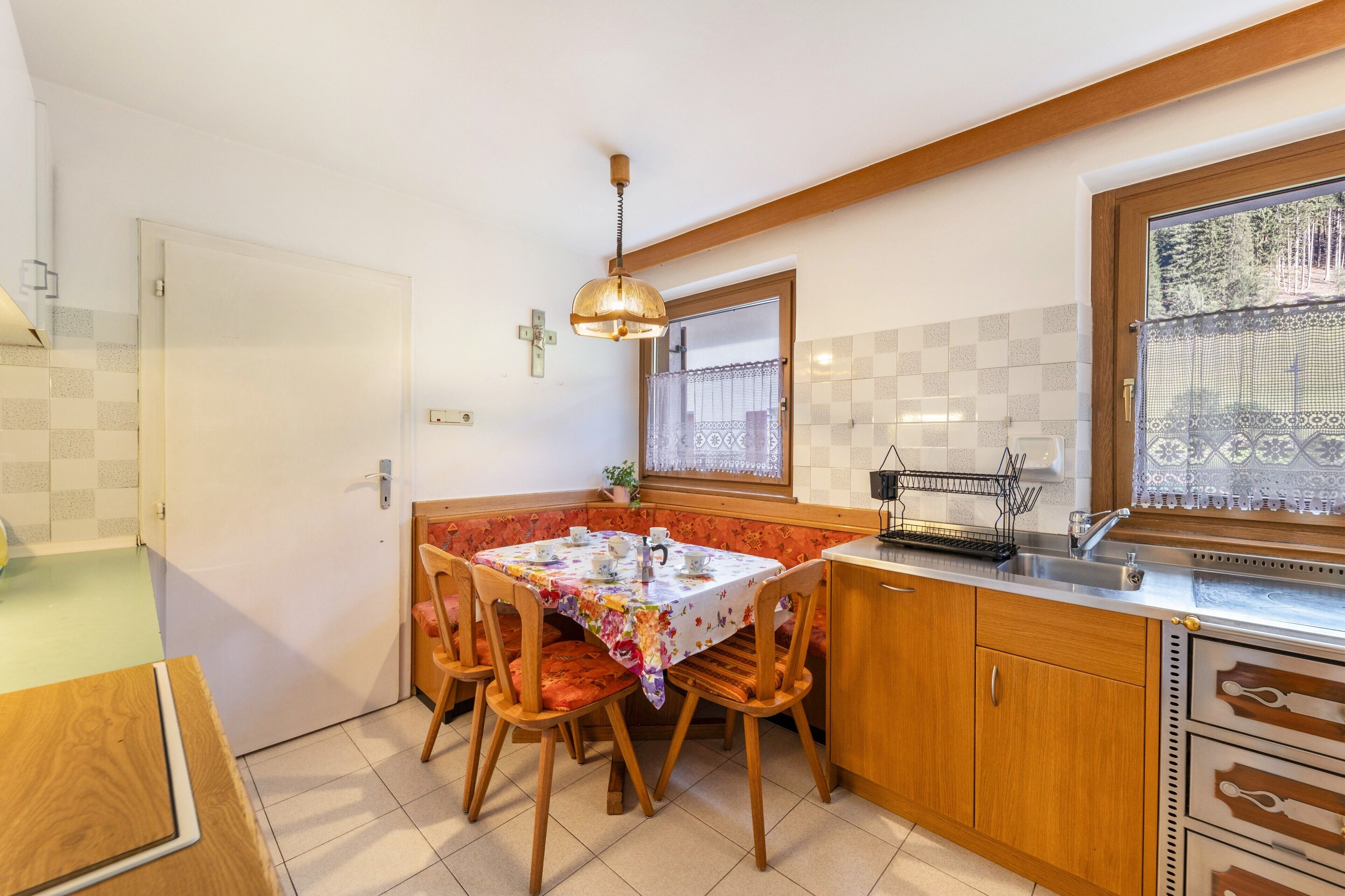 A kitchen with a dining table, chairs, a window with a view, and a sink.