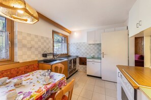 A compact kitchen with a dining table, chairs, a refrigerator, and a window with a view.