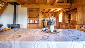 Un interior de madera con una mesa de comedor, estanterías, una zona de cocina y una chimenea.