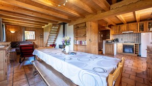 Un interior de madera con una mesa de comedor, bancos, una escalera y una zona de cocina.