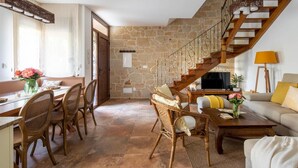A spacious living area with a stone wall, wooden staircase, wicker furniture, and a television. - Holiday Home 'Fogar Da Roda' with Private Terrace, Balcony and Wi-Fi (Vilagarcia de Arousa)