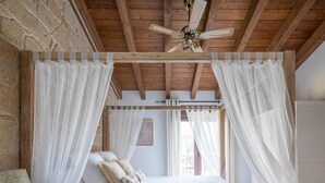 A bedroom with a four-poster bed, white bedding, a wooden ceiling, and a ceiling fan. - Holiday Home 'Fogar Da Roda' with Private Terrace, Balcony and Wi-Fi (Vilagarcia de Arousa)