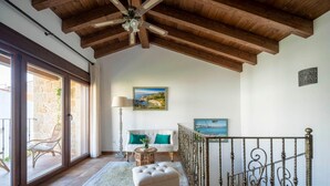 A spacious room with a high ceiling, a white sofa with teal cushions, a small round table, and a decorative railing. - Holiday Home 'Fogar Da Roda' with Private Terrace, Balcony and Wi-Fi (Vilagarcia de Arousa)