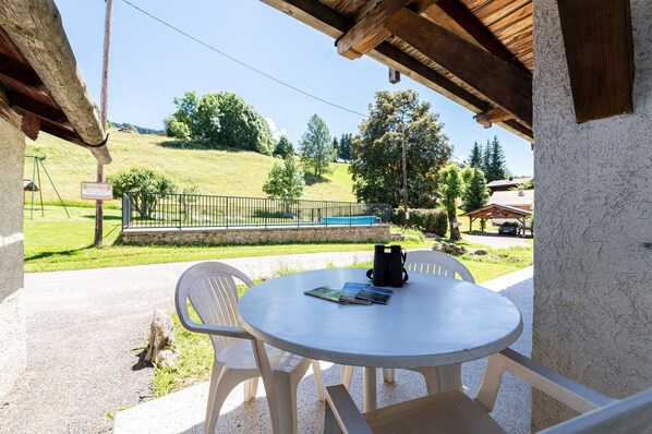 Eine Terrasse mit Tisch, Stühlen, einem Buch und einer Kaffeekanne.