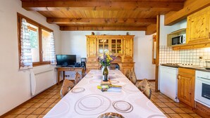 Un coin repas avec une longue table, des meubles de rangement en bois, un four à micro-ondes et un téléviseur.