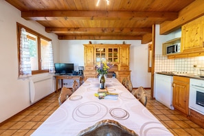 Un coin repas avec une longue table, des meubles de rangement en bois, un four à micro-ondes et un téléviseur.