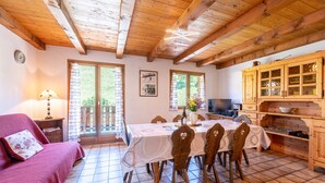 Une pièce chaleureuse avec un plafond en bois, une table à manger avec des chaises, un canapé et un coin cuisine équipé de placards.