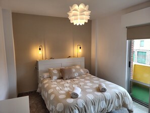 Une chambre à coucher comprenant un lit, deux lampes fixées au mur, un luminaire au plafond et une fenêtre donnant sur un paysage agréable.