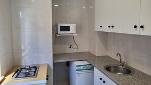 A compact kitchen with a gas stove, a microwave, a sink, and cabinets.