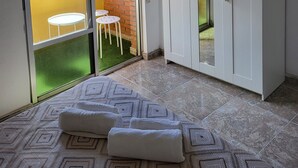 A room with a bed, a wardrobe, a sliding glass door to an outdoor area with a table and chairs, and a ceiling light fixture.