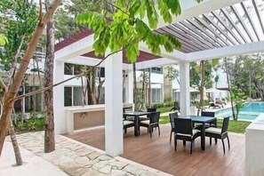 Un espace extérieur aménagé en terrasse, avec un coin salon abrité, des tables et des chaises.