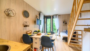 A modern room with a wooden desk, a bed, a TV, and a staircase. - Chalet 'Gîte Le Pieraline' with Mountain View, Private Terrace and Wi-Fi (Ventron)