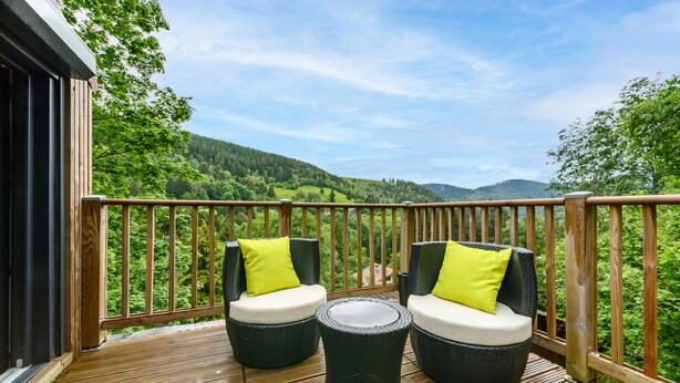 A wooden deck with wicker furniture and a view of a green landscape. - Chalet 'Gîte Le Pieraline' with Mountain View, Private Terrace and Wi-Fi (Ventron)