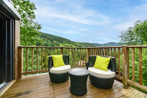 Un pontile in legno con mobili in vimini e vista su un paesaggio verde.