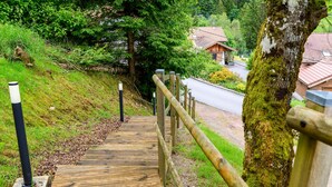 A wooden staircase leading uphill with a metal railing, surrounded by greenery and a building in the background. - Chalet 'Gîte Le Pieraline' with Mountain View, Private Terrace and Wi-Fi (Ventron)