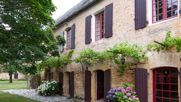 A stone building with multiple windows and doors, a stone pathway, and lush greenery. - Holiday Home 'Le Bel Prat' with Private Pool, Private Terrace and Wi-Fi (Domme)