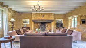 A room with stone walls, a fireplace, a chandelier, and two sofas. - Holiday Home 'Le Bel Prat' with Private Pool, Private Terrace and Wi-Fi (Domme)
