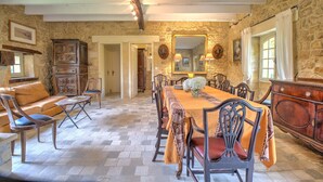 A dining area with a long table, chairs, and a stone wall. - Holiday Home 'Le Bel Prat' with Private Pool, Private Terrace and Wi-Fi (Domme)