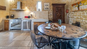 A kitchen with a stone wall, a stove, a sink, and a dining table with chairs.